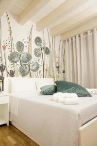 a white bed with green pillows in a bedroom at Villanova Sweet Home in Cagliari
