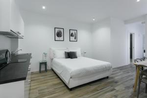 a white bedroom with a white bed and a table at Milanofierapartments in Milan