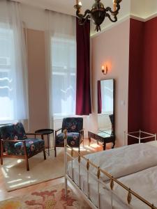 a bedroom with a bed and two chairs and a mirror at Madana apartman in Budapest