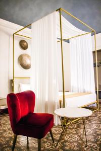 um quarto com uma cadeira vermelha e uma cama em Scene Suites Apartments em Catânia