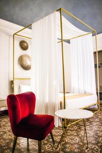 a room with a red chair and a bed at Scene Suites Apartments in Catania