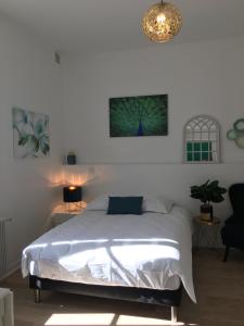 a white bedroom with a bed and a chandelier at Le Bahia centre la Brèche wifi linge de pressing in Niort
