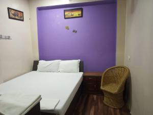 1 dormitorio con pared morada, cama y silla en Kanha Paying Guest House, en Varanasi