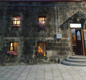 un antico edificio in pietra con un fuoco alle finestre di Hye Aspet Հայ Ասպետ a Gyumri