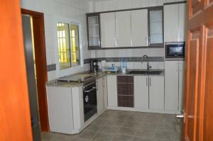 - une cuisine avec des placards blancs et un évier dans l'établissement Le VIP du Petit Génie, à Yaoundé