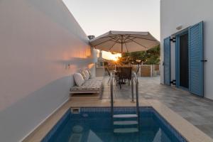 a house with a swimming pool and an umbrella at Tanyas Cozy House in Kamilari