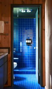 a blue tiled bathroom with a shower with a toilet at Captain Whidbey in Coupeville