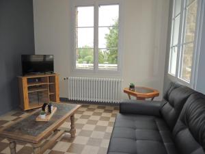 a living room with a couch and a tv at Le Lutice in Aunay-sur-Odon