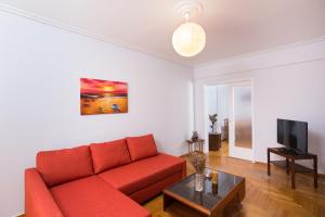 un soggiorno con divano rosso e TV di Christina's flat ad Atene