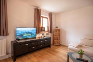 a living room with a flat screen tv on a dresser at Salven-Lodge in Hopfgarten im Brixental