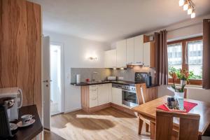 a kitchen with white cabinets and a wooden table at Salven-Lodge in Hopfgarten im Brixental