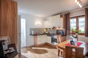 kuchnia z białymi szafkami i drewnianym stołem w obiekcie Salven-Lodge w mieście Hopfgarten im Brixental