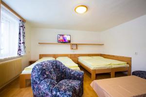 a room with two beds and a chair and a tv at U Kapličky in Rokytnice nad Jizerou