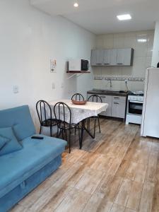 a living room with a blue couch and a kitchen at Apartamento aluguel temporada Torres-RS in Torres