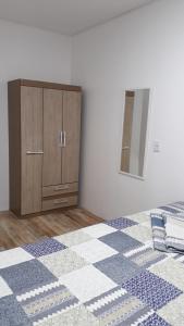 a bedroom with a bed with a dresser and a mirror at Apartamento aluguel temporada Torres-RS in Torres