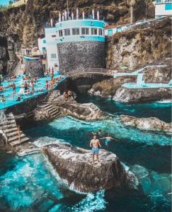 a man standing on a rock in the water at Doca do Cavacas Apartment in Funchal