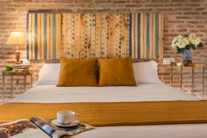 - une chambre avec un lit doté d'oreillers jaunes et une table avec un plateau dans l'établissement Misterhost Triana Patio de las Flores, à Séville