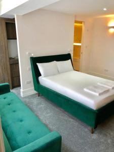 1 dormitorio con 1 cama y 1 sofá verde en Widegate Residential en Londres