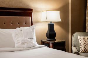 a bed with a lamp on a table next to a chair at Red Deer Resort & Casino in Red Deer