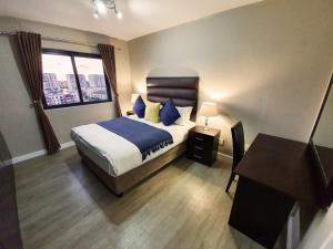 a bedroom with a bed and a desk and a window at Knightsbridge Luxury Apartments in Cape Town +51 photos