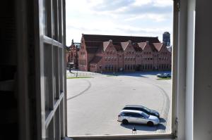 un coche blanco estacionado en un estacionamiento frente a un edificio en Ołowianka B&B, en Gdansk