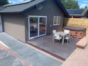 a patio with a table and chairs and a grill at Woodburn Lodge in Dumfries