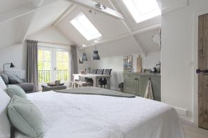 a bedroom with a large white bed and a kitchen at B&B de Linge in Gellicum
