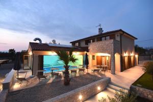a house with a patio with a table and chairs at Villa Muskatel KRK -with heated covered pool in Krk