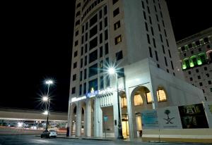 a large white building with street lights in front of it at Hayah Al Waha Hotel in Al Madinah