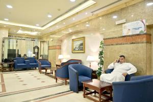 um homem sentado numa sala de espera a falar ao telemóvel em Hayah Al Waha Hotel em Medina