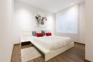 een witte slaapkamer met een groot wit bed met rode kussens bij UBICACIÓN INMEJORABLE REFORMADO LUJO in Bilbao