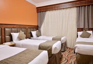 a hotel room with three beds and orange walls at Hayah Plaza Hotel in Medina