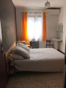 a bedroom with a bed and a window with orange curtains at U Ricordu in Prunelli-di-Fiumorbo