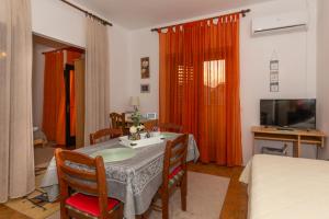 a living room with a table and chairs and a television at Apartman Zorica in Biograd na Moru