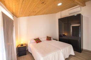 1 dormitorio con cama blanca y ventana grande en Apartamentos Cáceres Turístico en Cáceres