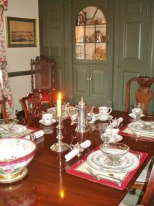 uma mesa de jantar com uma vela e pratos em Newport House Bed & Breakfast em Williamsburg