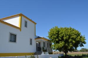 Una casa blanca con un árbol delante. en Casal dos Cantos, en Quinta do Anjo