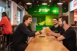 un grupo de hombres sentados alrededor de una mesa bebiendo cerveza en Innbox - Centro, en Florianópolis