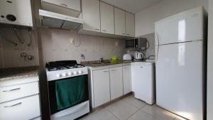 uma cozinha com armários brancos, um fogão e um frigorífico em Apartamento 4 de Enero em Santa Fé