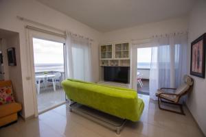 a living room with a green couch and a television at Apartamento en Playa Chica, Las Gaviotas in Santa Cruz de Tenerife
