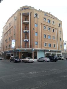 duży budynek z samochodami zaparkowanymi przed nim w obiekcie امواج للشقق المخدومة - Amwaj suites w mieście Al-Chubar