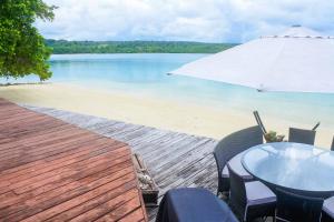 un tavolo e sedie con ombrellone su una spiaggia di Santo Sunset Beach Villas on Surunda Bay a Luganville