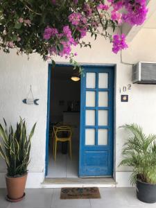 una puerta azul en una casa con flores rosas en Lindo Apartamento em Arraial, en Arraial do Cabo