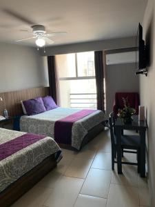 1 dormitorio con 2 camas y mesa con silla en Hotel FG en León