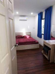 a bedroom with a bed with red sheets and blue curtains at Happy Home Hostel in Lat Krabang
