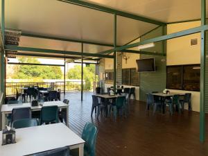 a restaurant with tables and chairs and a television at Victoria Village in Katherine