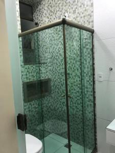 La salle de bains est pourvue d'une douche en verre et de toilettes. dans l'établissement Estilo Residence II, à São Lourenço