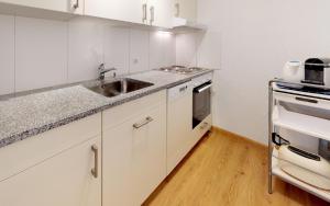 Una cocina con gabinetes blancos y un fregadero. en Ova Cotschna 705, en St. Moritz