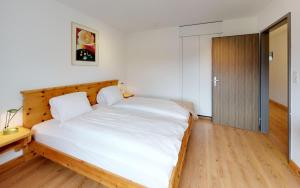 1 dormitorio con 1 cama blanca grande y cabecero de madera en Ova Cotschna 705, en St. Moritz