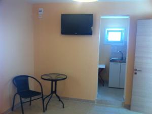 Habitación con mesa, sillas y TV en la pared. en Melissa Rooms en Agios Kirykos